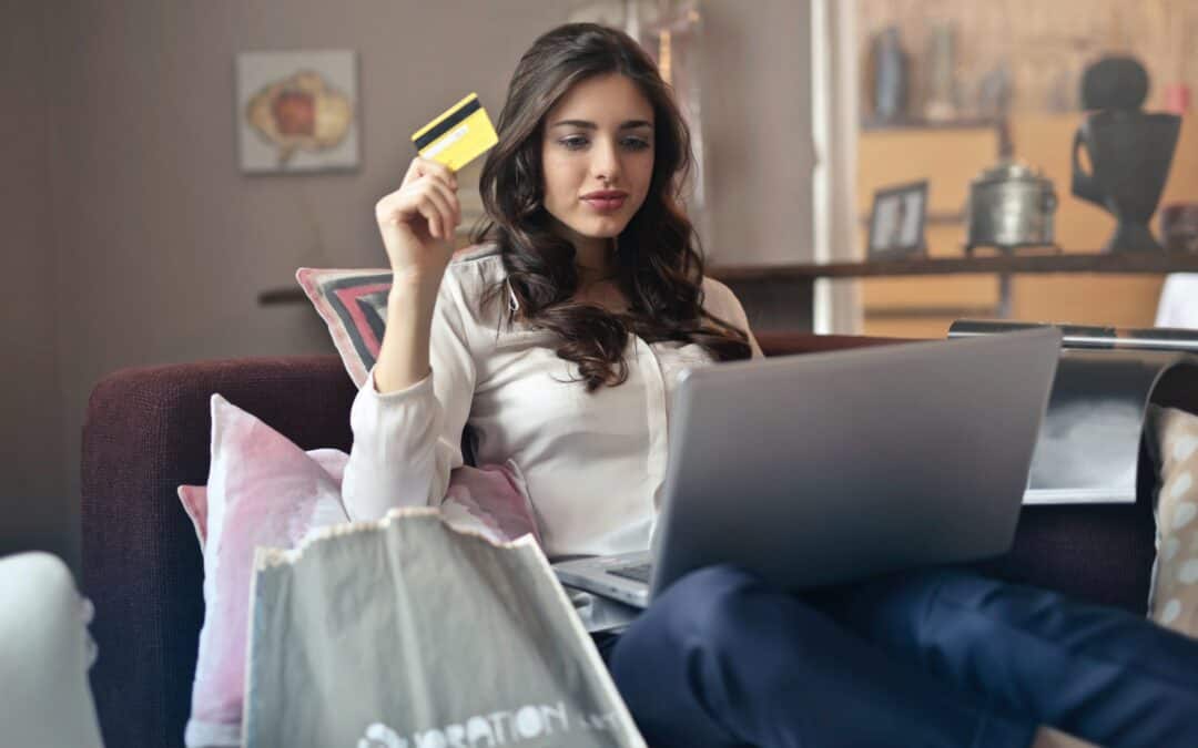 a woman sat at a laptop making a purchase with a UK issued visa credit card. This will no longer be possible on Amazon from January 2022